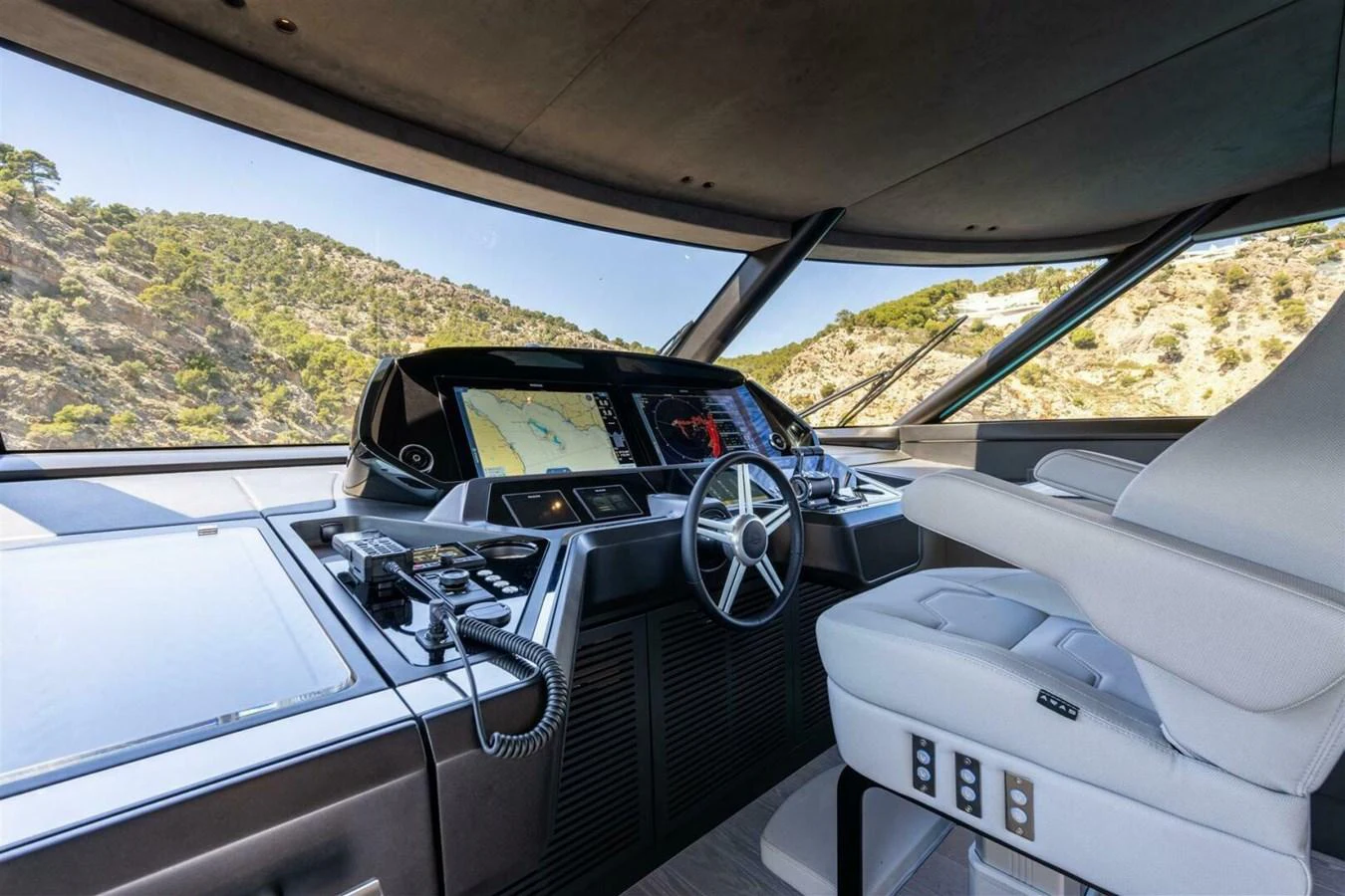 The helm station features advanced navigation equipment and a comfortable captain's chair, offering panoramic views. aboard 90 OCEAN ENCLOSED Yacht for Sale