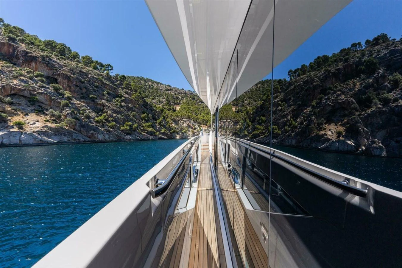 A sleek yacht deck with reflective glass panels cruising through a scenic coastal area. aboard 90 OCEAN ENCLOSED Yacht for Sale
