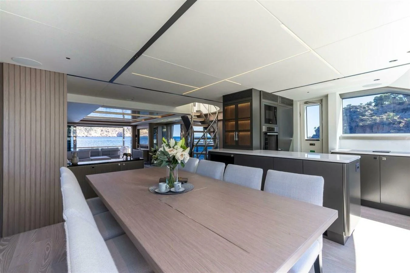 The yacht's dining area features a modern table with plush seating and large windows offering scenic views. aboard 90 OCEAN ENCLOSED Yacht for Sale
