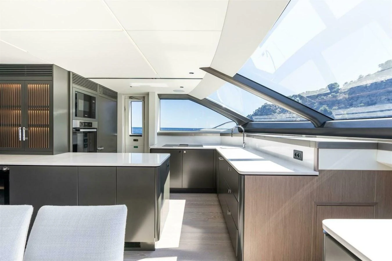 A modern galley with sleek cabinetry and expansive windows offering stunning views. aboard 90 OCEAN ENCLOSED Yacht for Sale