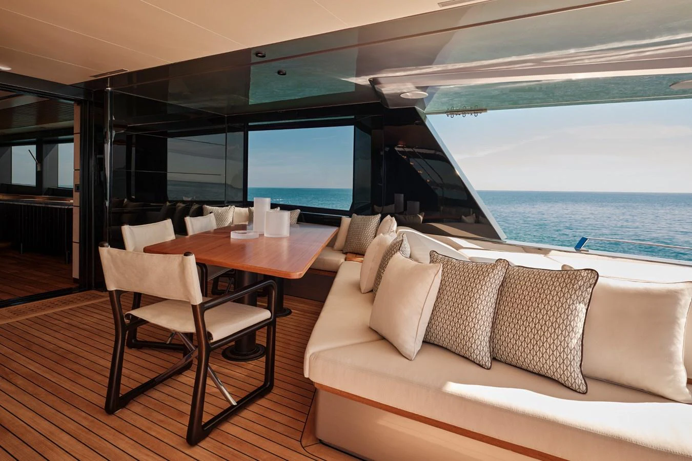 The aft deck features a stylish dining area with a wooden table and comfortable seating, offering stunning ocean views. aboard WALLYWHY200 Yacht for Sale