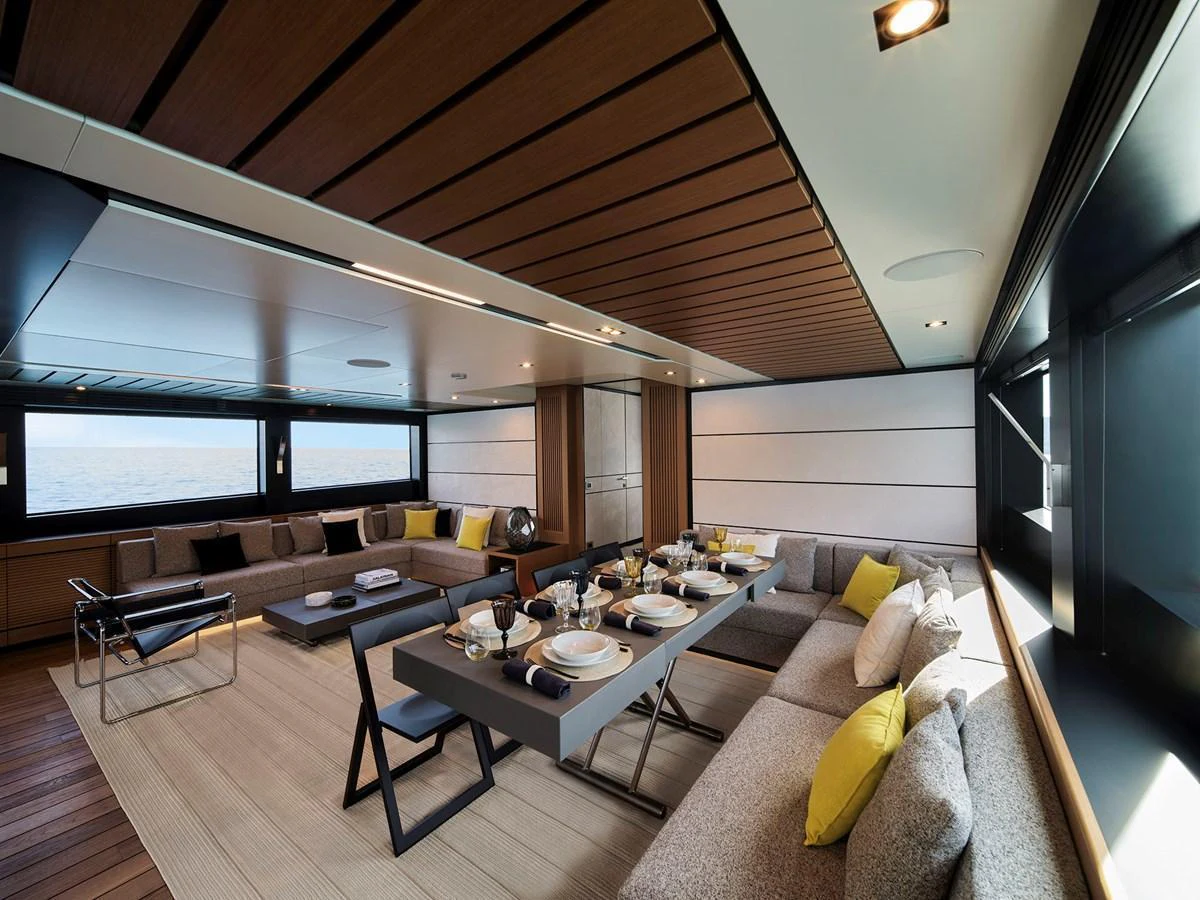 The salon features a spacious and modern design with ample seating and a dining area, accented by large windows offering stunning sea views. aboard WALLYWHY200 Yacht for Sale
