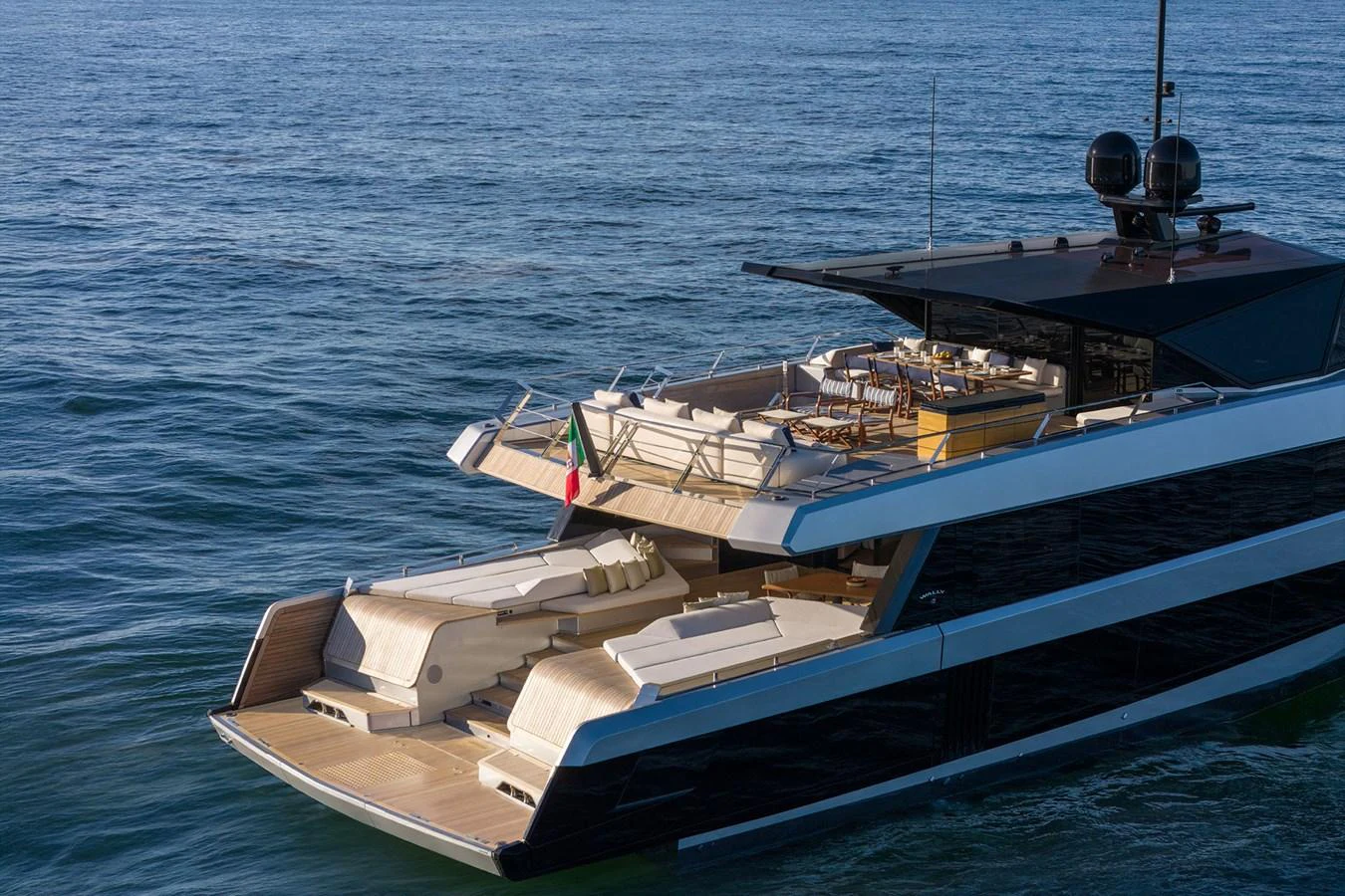 A sleek yacht with an inviting aft deck featuring sun loungers and a dining area, cruising on calm waters. aboard WALLYWHY200 Yacht for Sale