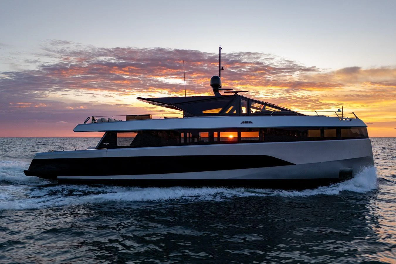 A sleek yacht cruises through the water at sunset, showcasing its modern design and elegant lines. aboard WALLYWHY200 Yacht for Sale