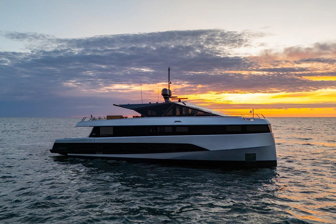 A sleek and modern yacht glides on the water at sunset, showcasing its elegant design against a stunning sky. aboard WALLYWHY200 Yacht for Sale