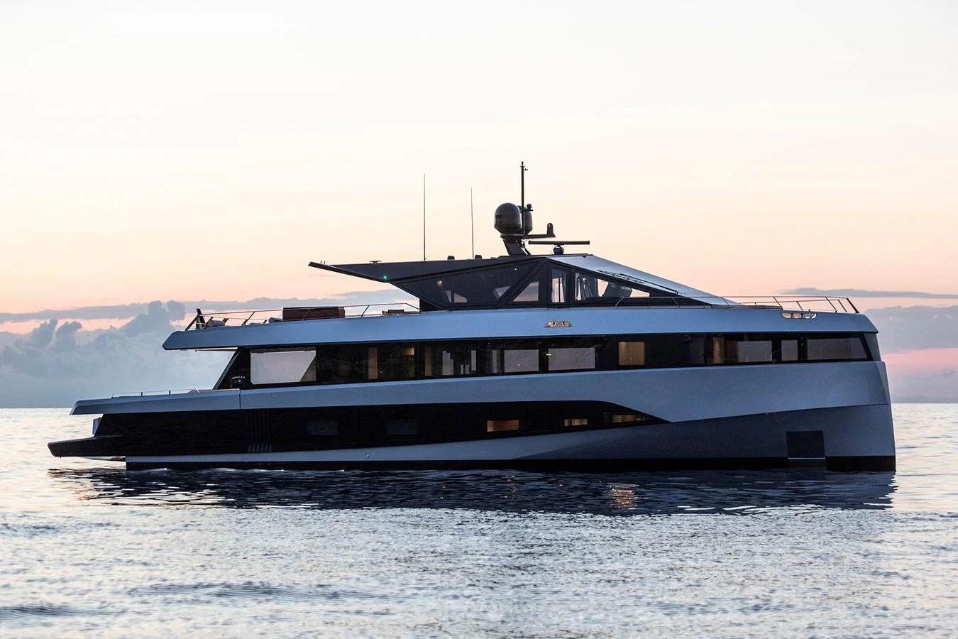 A sleek and modern yacht glides gracefully on calm waters at sunset. aboard WALLYWHY200 Yacht for Sale
