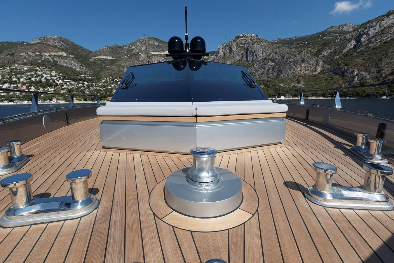 The foredeck of the yacht features sleek lines and polished fittings against a backdrop of scenic coastal mountains. aboard WALLYWHY200 Yacht for Sale