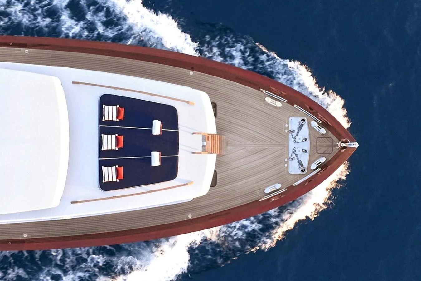 The foredeck of the yacht features a sleek design with sun loungers and a polished wooden deck. aboard PICCHIOTTI 24 Yacht for Sale