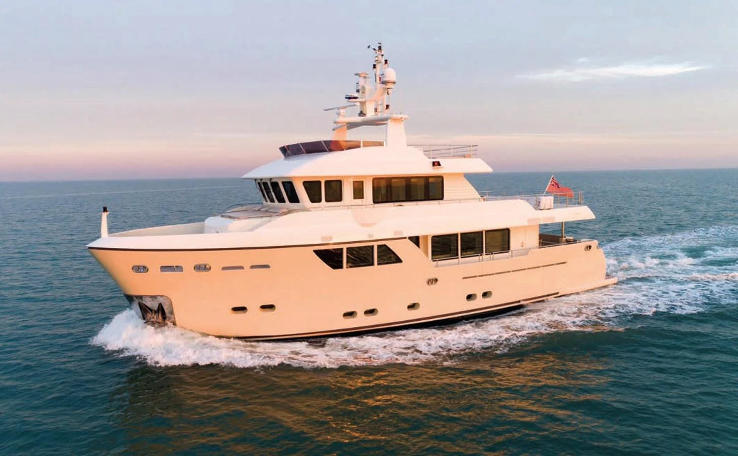 A luxurious yacht cruises smoothly on the open sea during a serene sunset. aboard STELLA DEL NORD Yacht for Sale