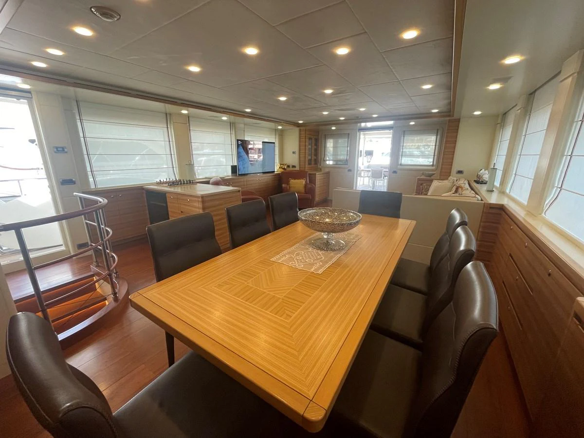 The yacht's dining area features a spacious table with comfortable seating, surrounded by large windows for natural light. aboard STELLA DEL NORD Yacht for Sale
