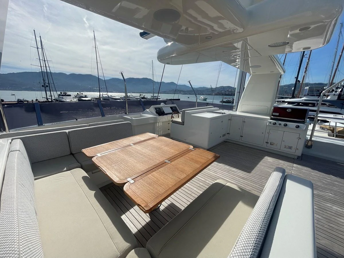 The aft deck features a spacious seating area with a wooden dining table, perfect for alfresco dining. aboard STELLA DEL NORD Yacht for Sale