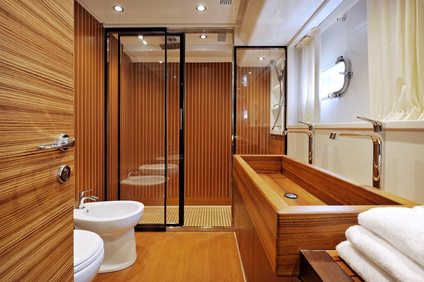 The yacht's bathroom features elegant wood paneling, a modern sink, and a spacious shower area. aboard SARNICO GRANDE HULL #3 Yacht for Sale