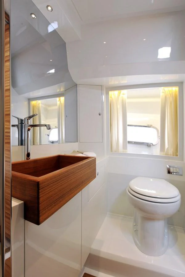 A sleek and modern yacht bathroom with a wooden sink and contemporary fixtures. aboard SARNICO GRANDE HULL #3 Yacht for Sale