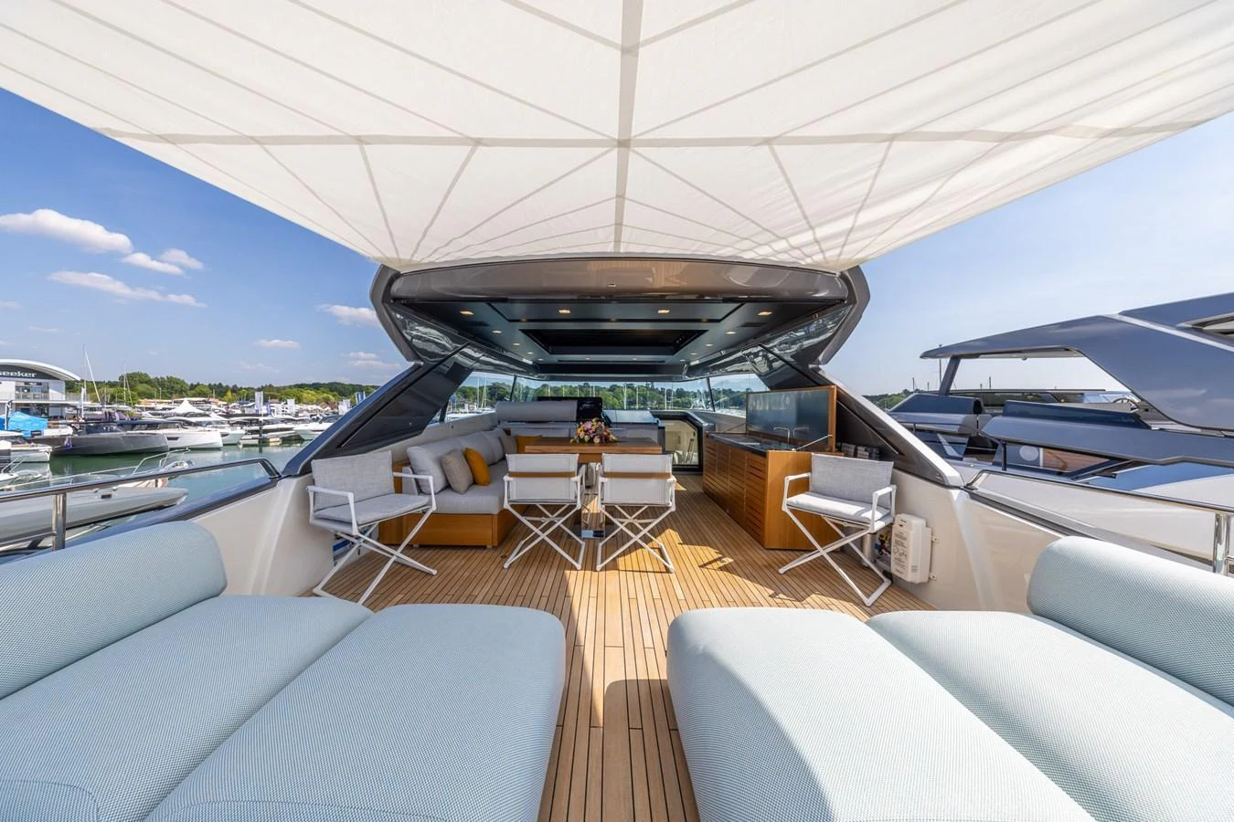 The flybridge offers a spacious and luxurious outdoor lounging area with comfortable seating and a shaded canopy. aboard SX76 #144 Yacht for Sale