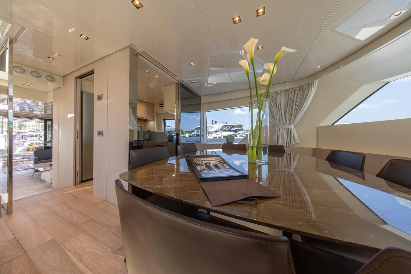 The yacht's dining area features a sleek table with elegant decor and ample seating, bathed in natural light. aboard SX76 #144 Yacht for Sale