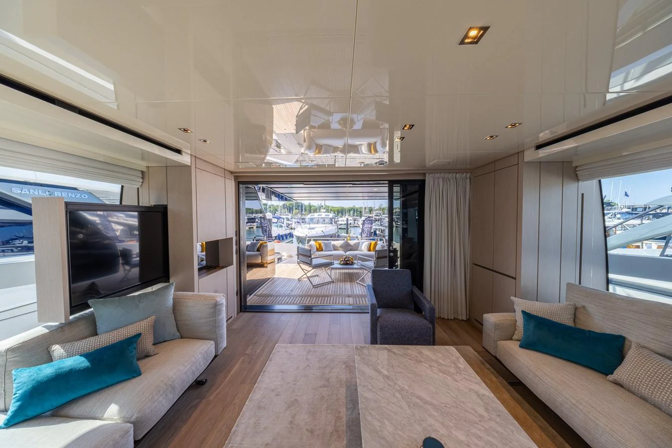 The salon features plush seating and a view of the aft deck through large sliding glass doors. aboard SX76 #144 Yacht for Sale