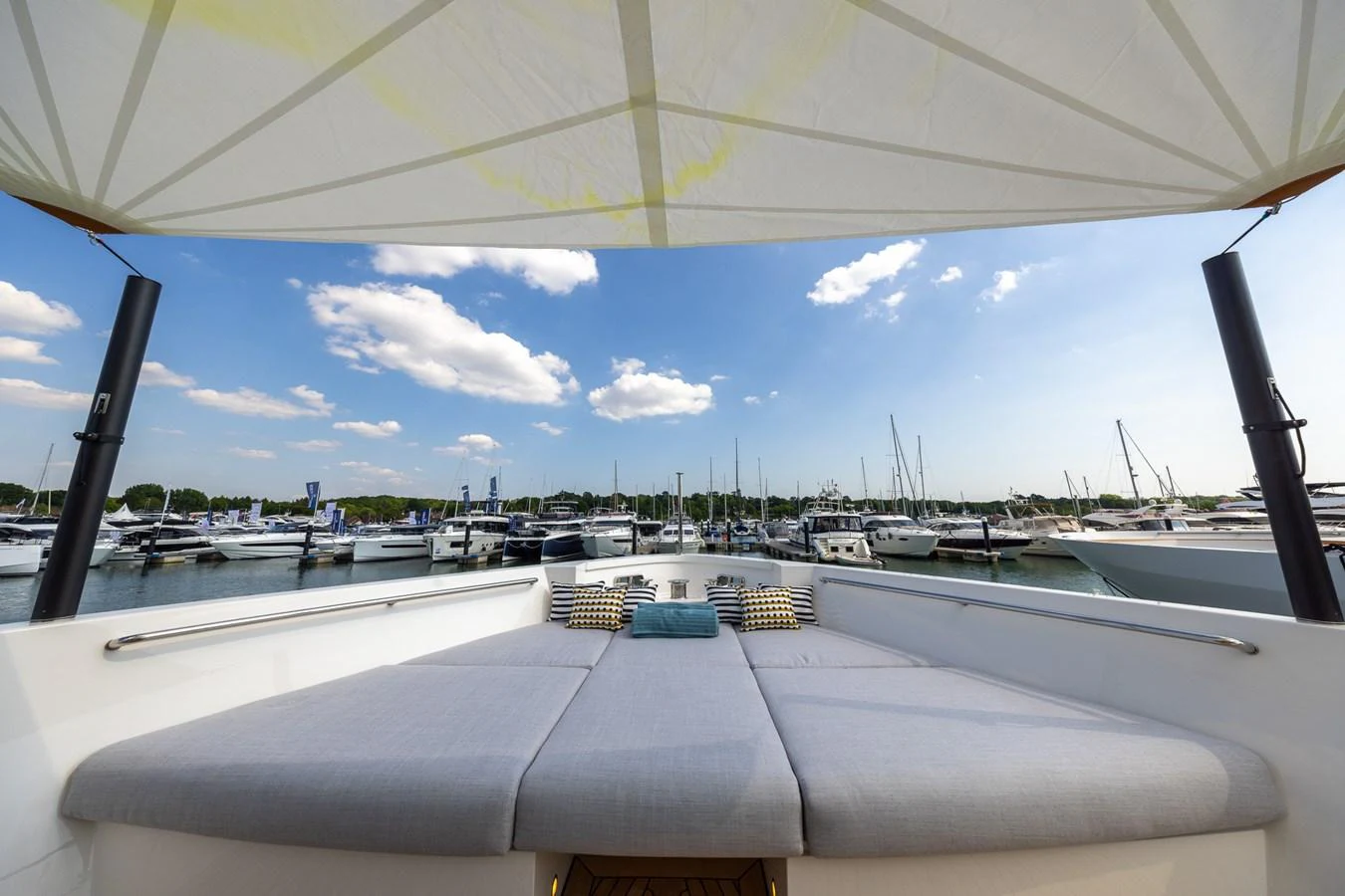 The sundeck offers a spacious and comfortable lounging area with a canopy providing shade and a view of the marina. aboard SX76 #144 Yacht for Sale