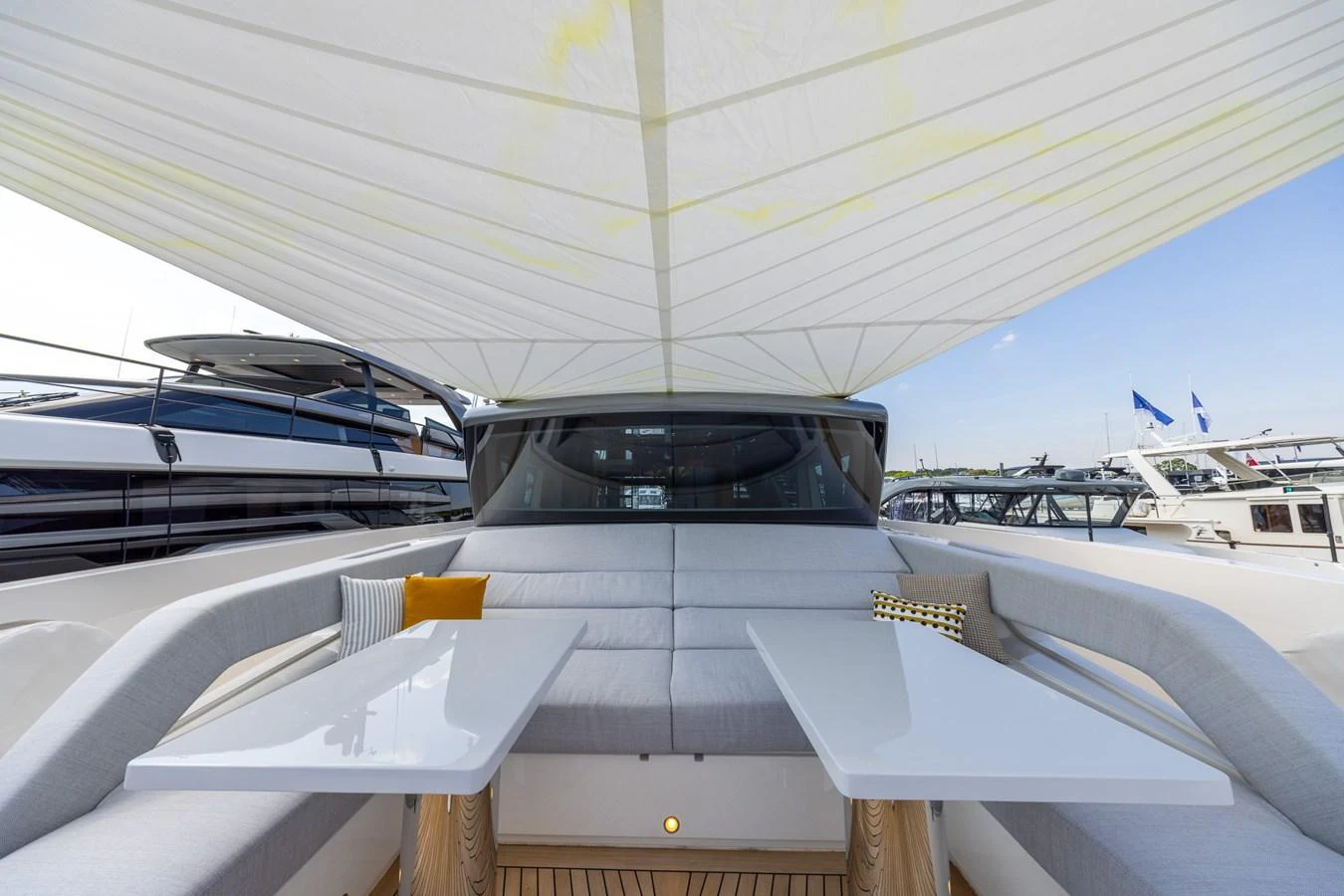 The aft deck features a stylish and comfortable seating area with two sleek tables under a shaded canopy. aboard SX76 #144 Yacht for Sale