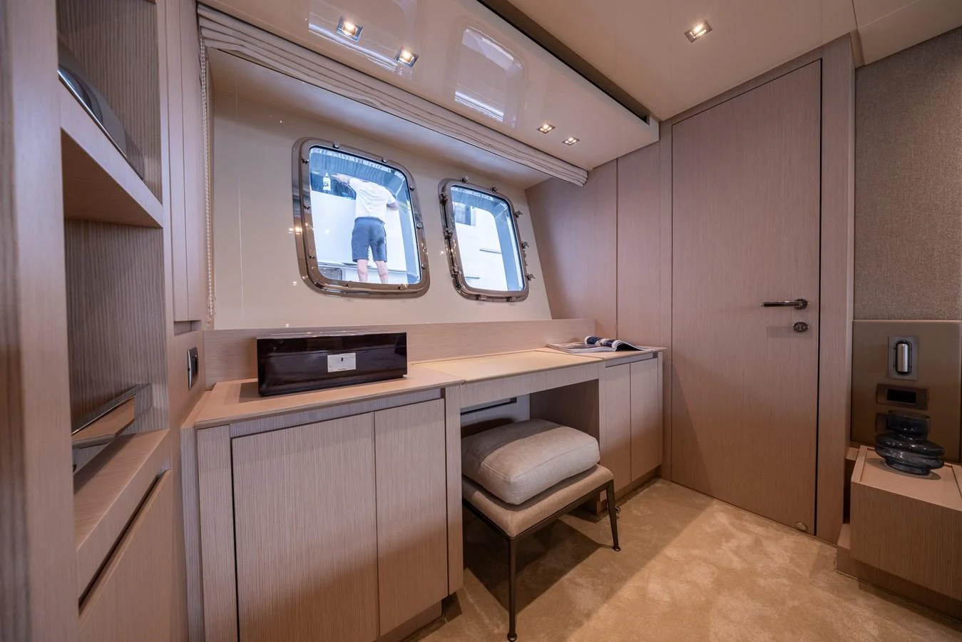 A sophisticated office space with a desk, stool, and large windows offering natural light. aboard SX76 #144 Yacht for Sale