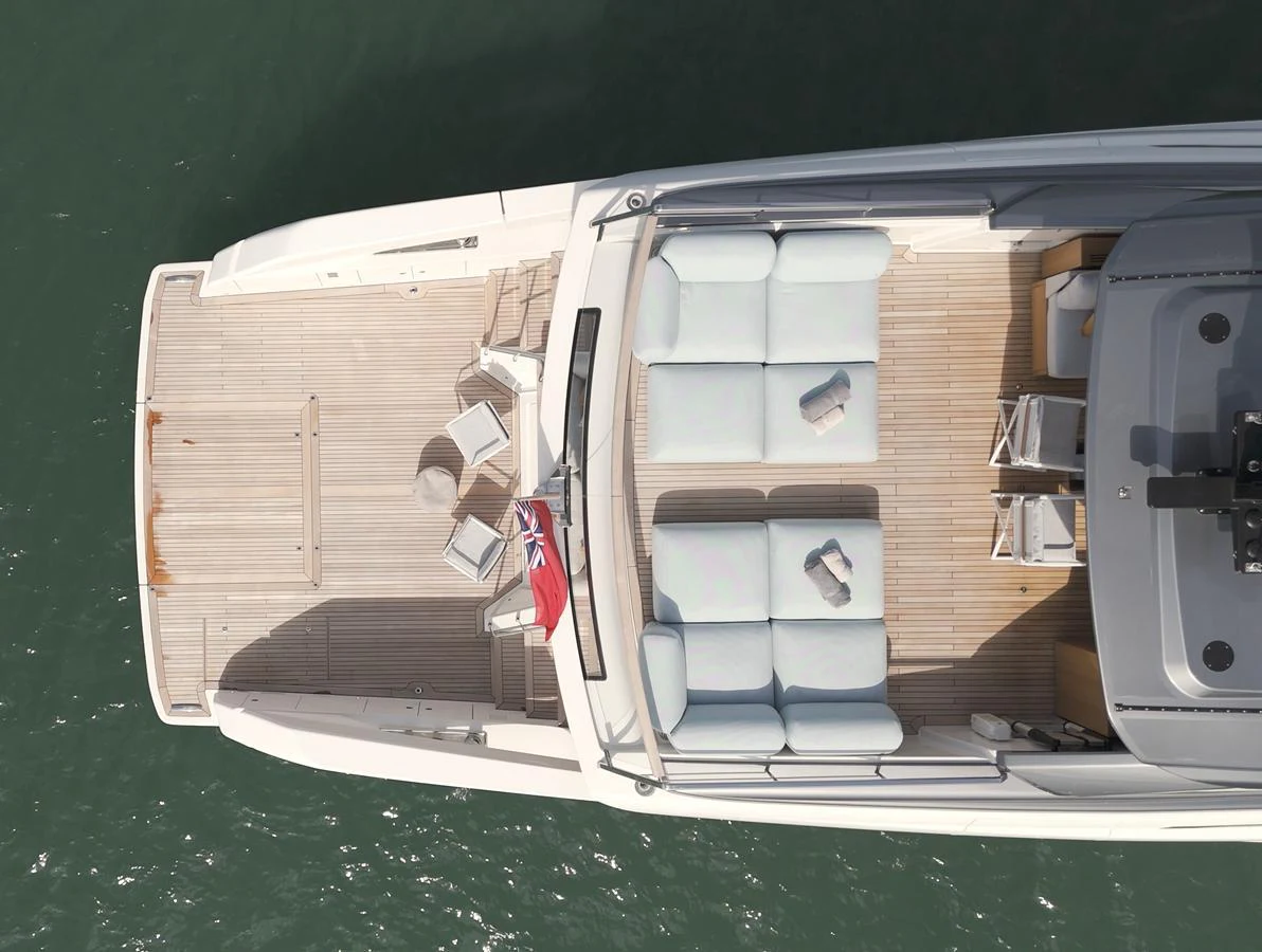 The yacht's aft deck features a spacious lounging area with comfortable seating and a flag proudly displayed. aboard SX76 #144 Yacht for Sale
