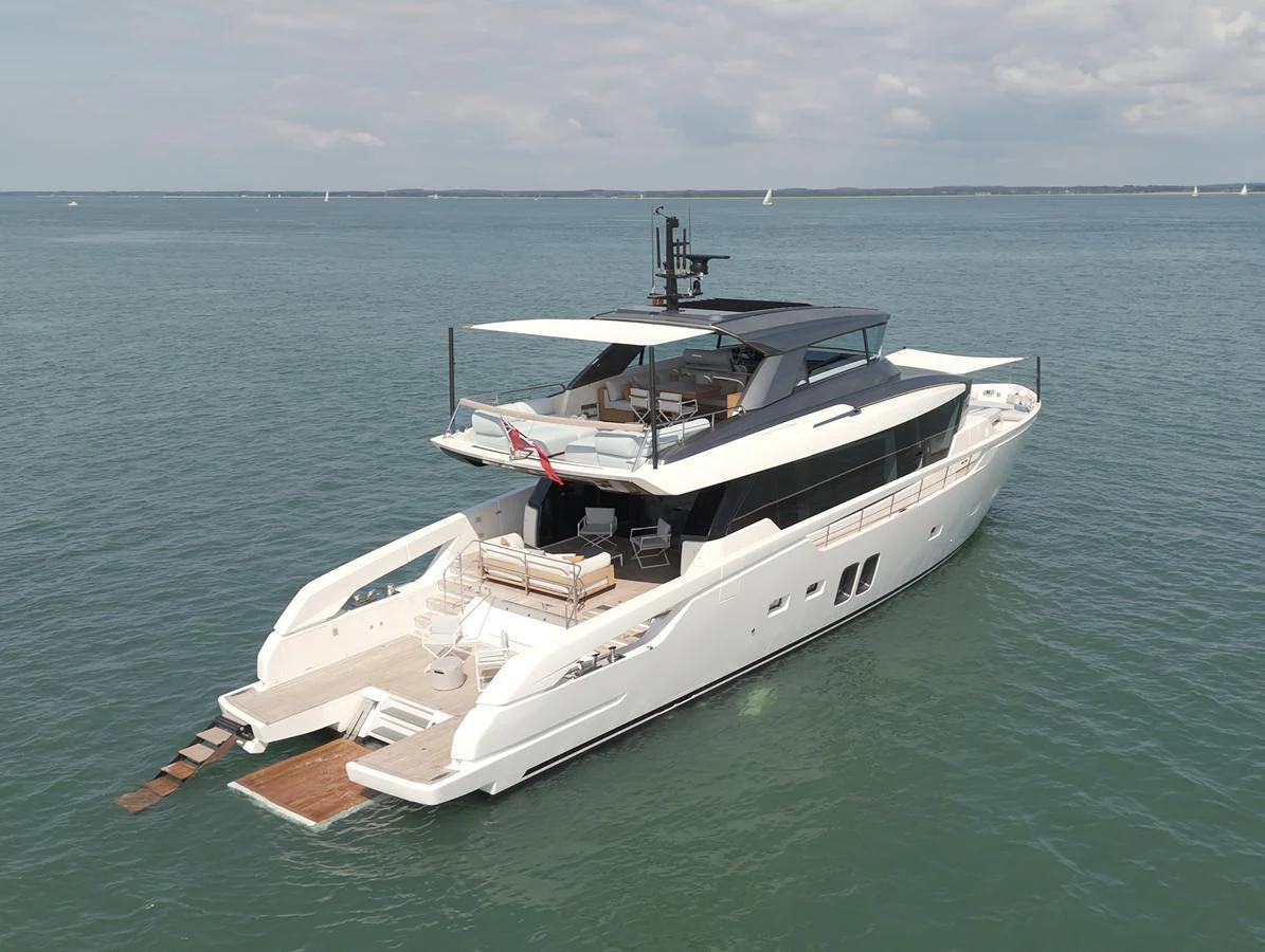A sleek and modern yacht glides gracefully on calm waters under a partly cloudy sky. aboard SX76 #144 Yacht for Sale