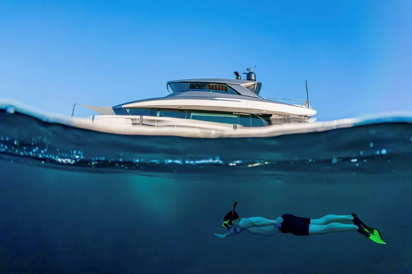 A sleek yacht is captured from a unique perspective, with a snorkeler swimming in the foreground. aboard FIREFLY Yacht for Sale