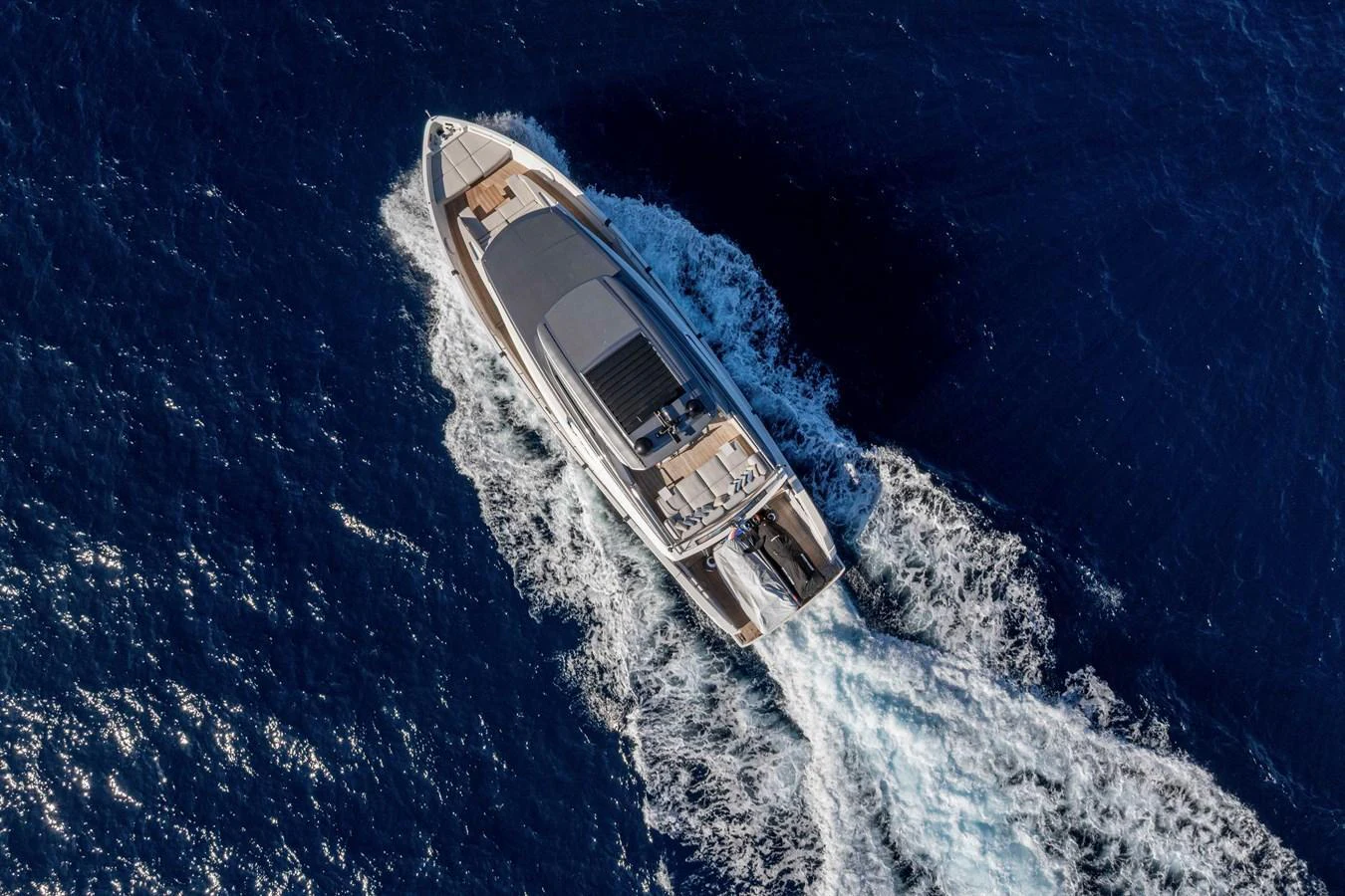 A luxurious yacht cruises through the deep blue sea, leaving a trail of white wake behind. aboard FIREFLY Yacht for Sale