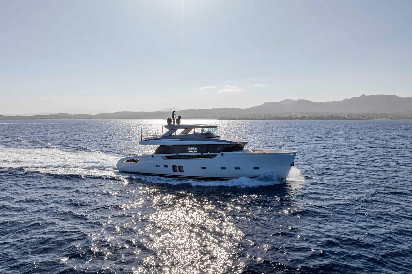 A sleek yacht cruises gracefully on the open sea under a clear sky. aboard FIREFLY Yacht for Sale