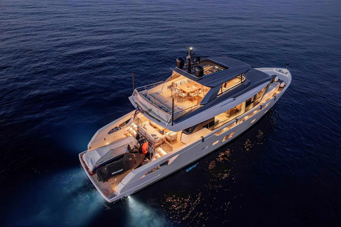 A stunning yacht cruises through the water at dusk, illuminated by warm lights. aboard FIREFLY Yacht for Sale