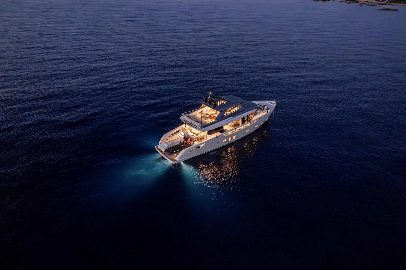 A luxurious yacht cruises gracefully on calm waters at dusk, illuminated by elegant lighting. aboard FIREFLY Yacht for Sale