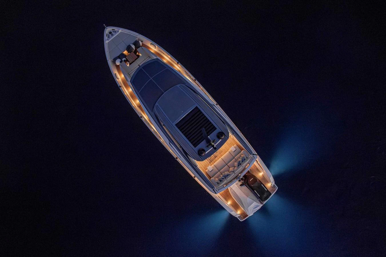A stunning aerial view of a yacht illuminated at night, showcasing its sleek design and elegant lighting. aboard FIREFLY Yacht for Sale
