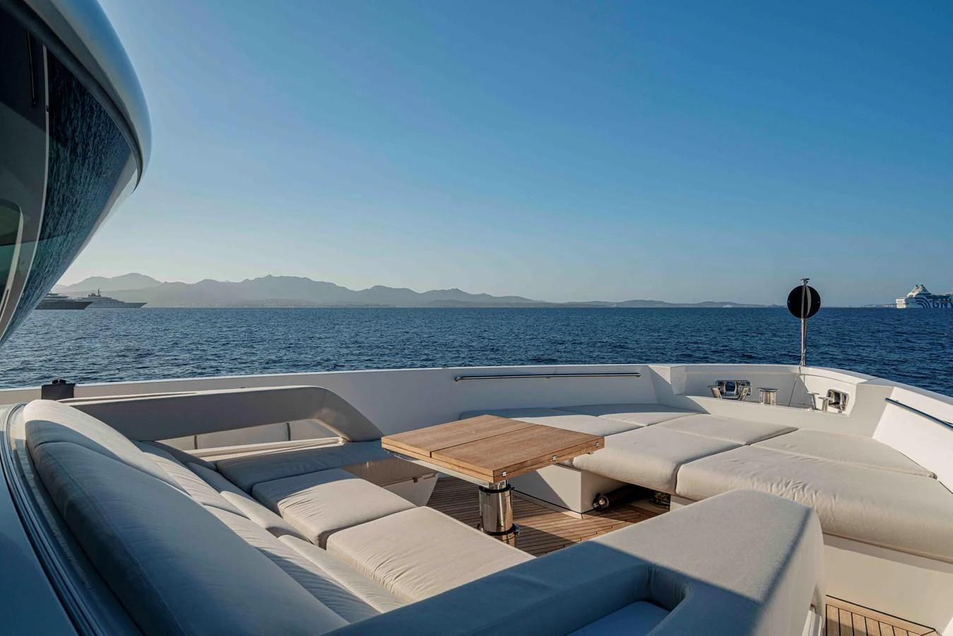 The foredeck features a spacious lounging area with a central wooden table, offering stunning views of the surrounding seascape. aboard FIREFLY Yacht for Sale