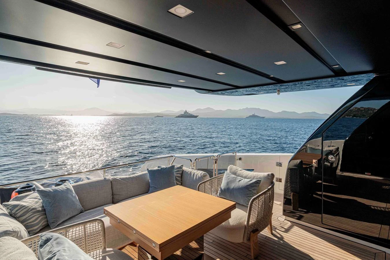 The aft deck offers a comfortable seating area with a wooden table, perfect for enjoying the scenic ocean views. aboard FIREFLY Yacht for Sale