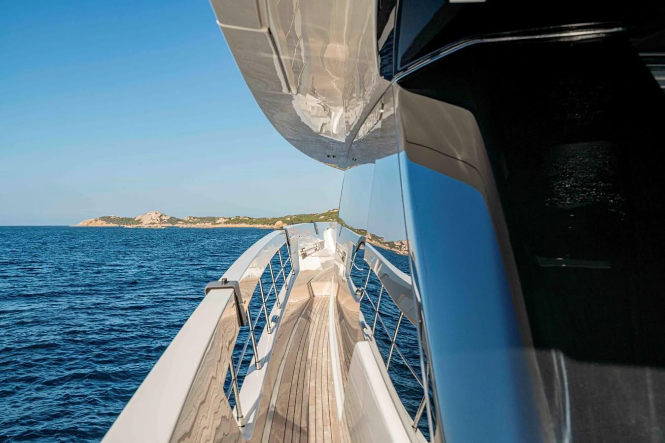 A sleek yacht cruising along a serene coastline with a clear view of the deck and surrounding waters. aboard FIREFLY Yacht for Sale