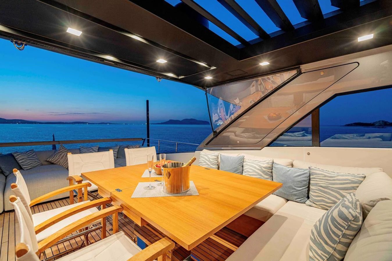 The aft deck features a luxurious dining area with a stunning sea view at sunset. aboard FIREFLY Yacht for Sale