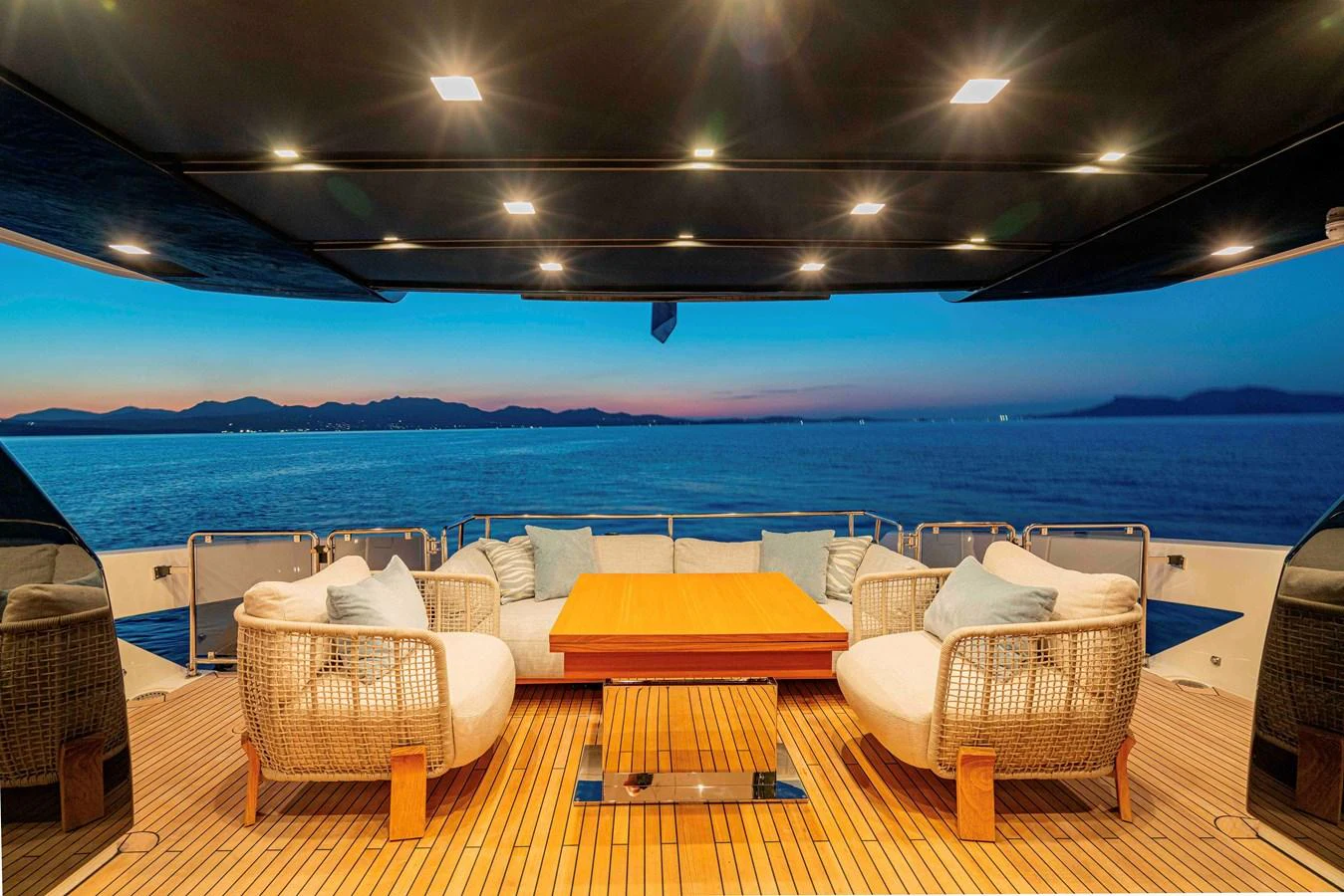 The aft deck offers a serene seating area with a stunning view of the sunset over the water. aboard FIREFLY Yacht for Sale