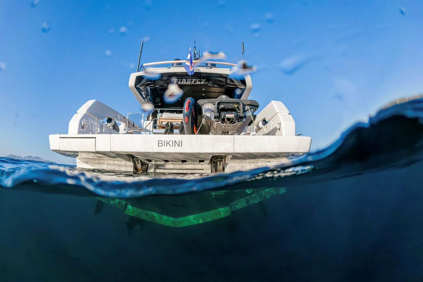 A sleek yacht is captured from a unique underwater perspective, showcasing its modern design and luxurious amenities. aboard FIREFLY Yacht for Sale