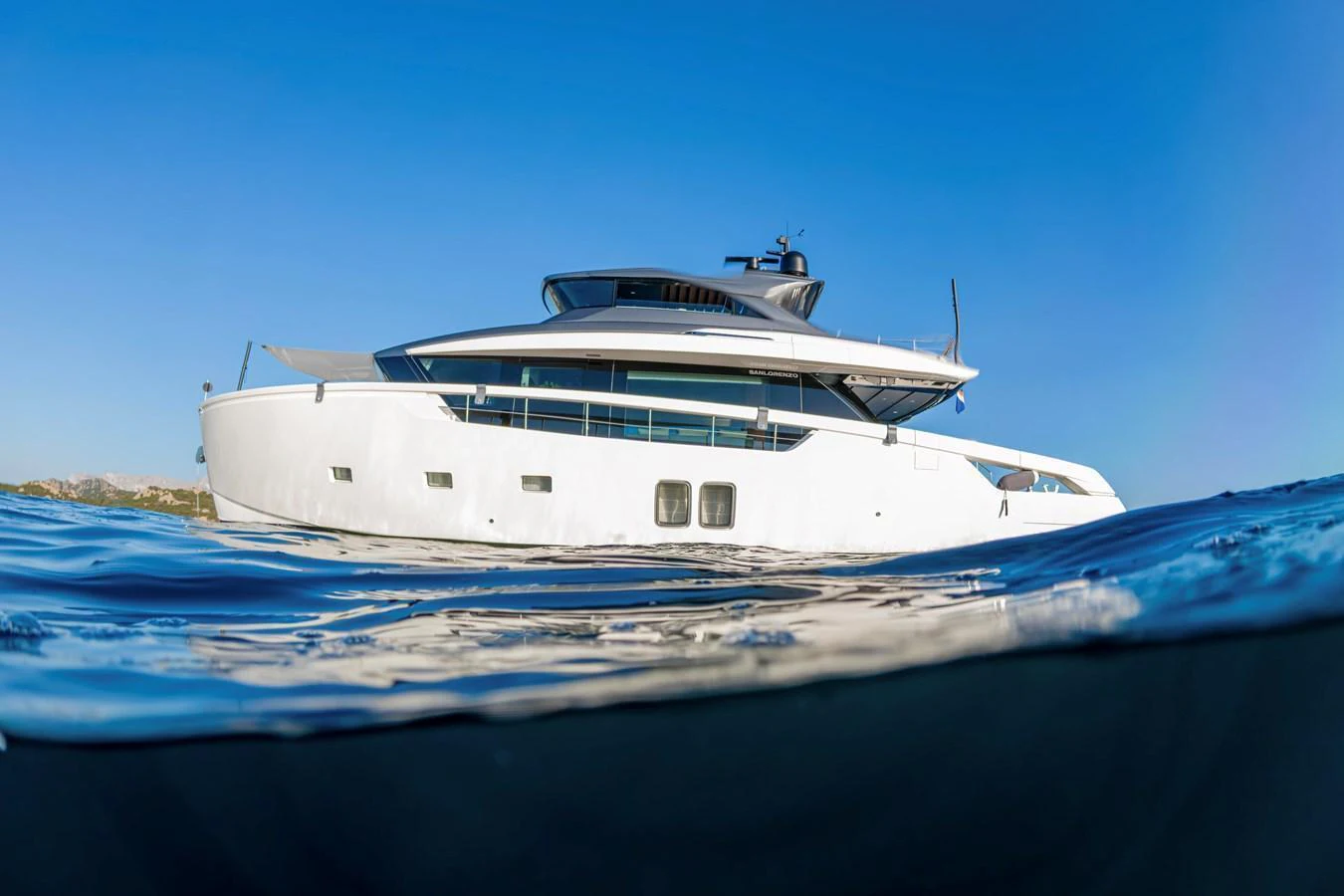 A sleek, modern yacht glides effortlessly on calm waters under a clear blue sky. aboard FIREFLY Yacht for Sale