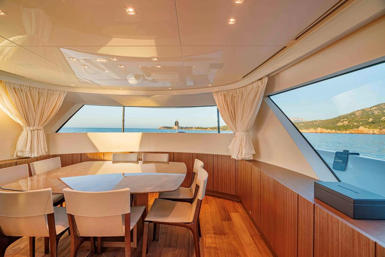 The yacht's dining area features a sleek table surrounded by modern chairs, with large windows offering stunning ocean views. aboard FIREFLY Yacht for Sale