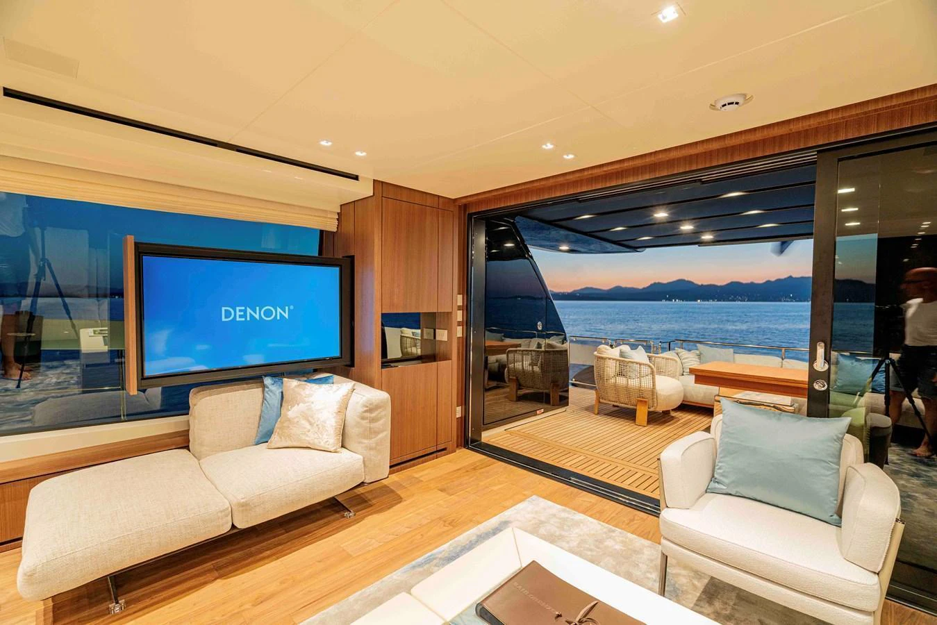 The yacht's interior features a cozy seating area with a view of the ocean through large windows and sliding glass doors. aboard FIREFLY Yacht for Sale