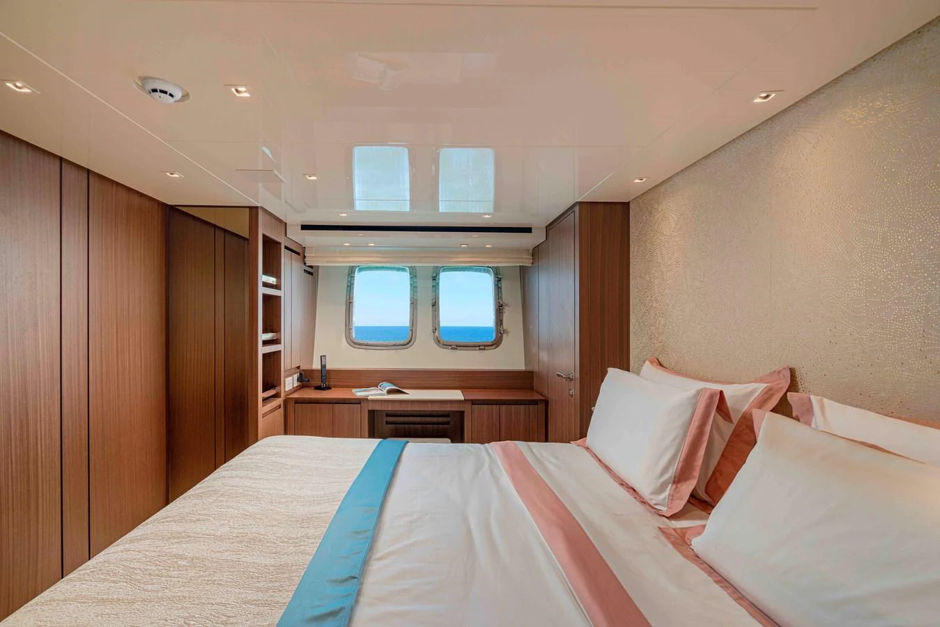 The stateroom features a cozy bed with elegant linens and a view of the sea through the windows. aboard FIREFLY Yacht for Sale