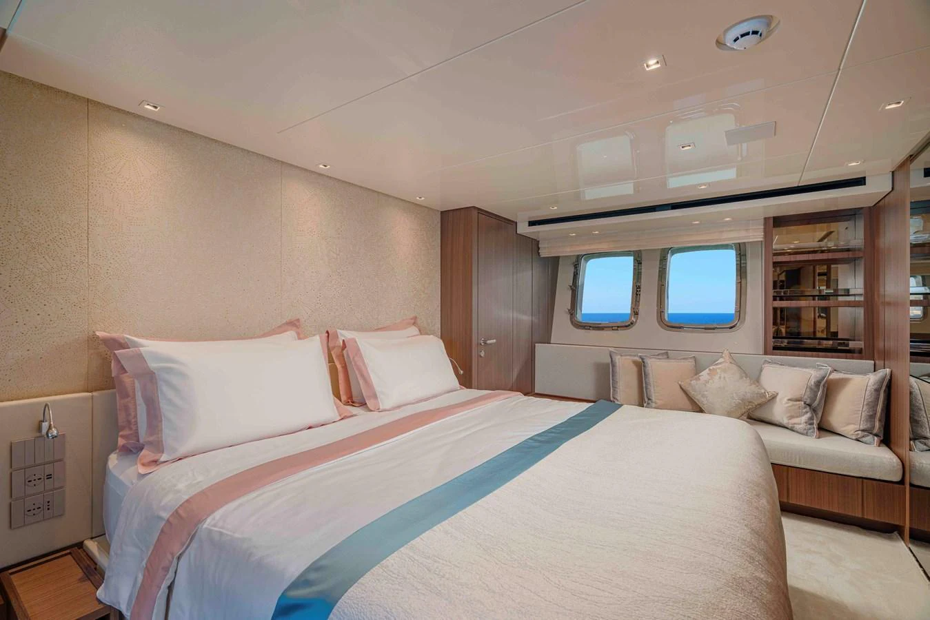 The stateroom features a luxurious bed with elegant bedding and a cozy seating area by the windows. aboard FIREFLY Yacht for Sale