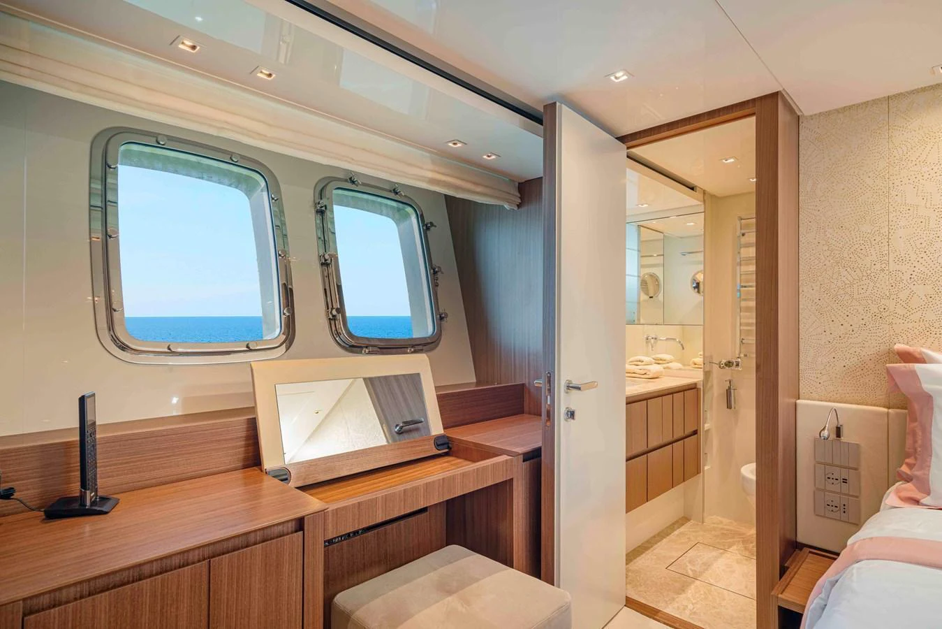 A luxurious stateroom with a view of the sea through two large windows, featuring a vanity desk and an ensuite bathroom. aboard FIREFLY Yacht for Sale