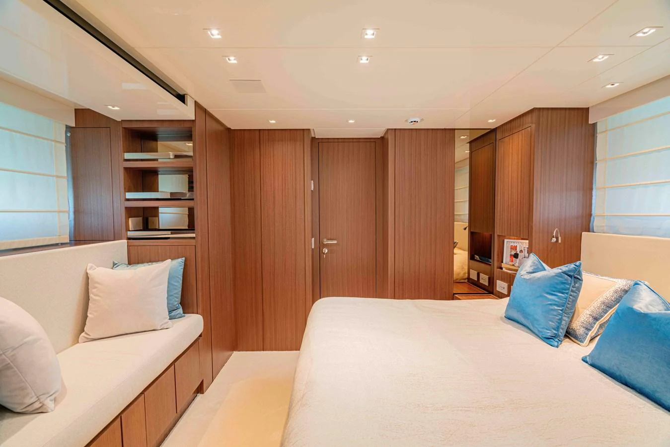 The stateroom features a spacious bed, elegant wood paneling, and ample natural light. aboard FIREFLY Yacht for Sale