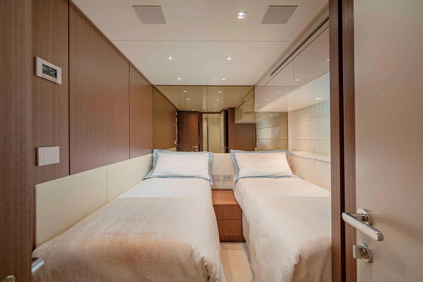 A cozy twin stateroom with modern wood paneling and soft lighting. aboard FIREFLY Yacht for Sale