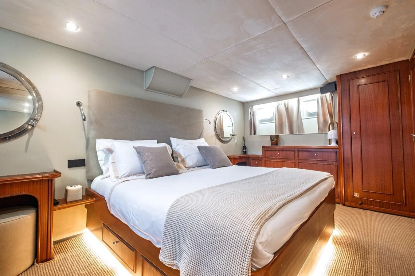 The stateroom features a plush bed with elegant bedding, warm wood accents, and ample natural light. aboard STALCA Yacht for Sale