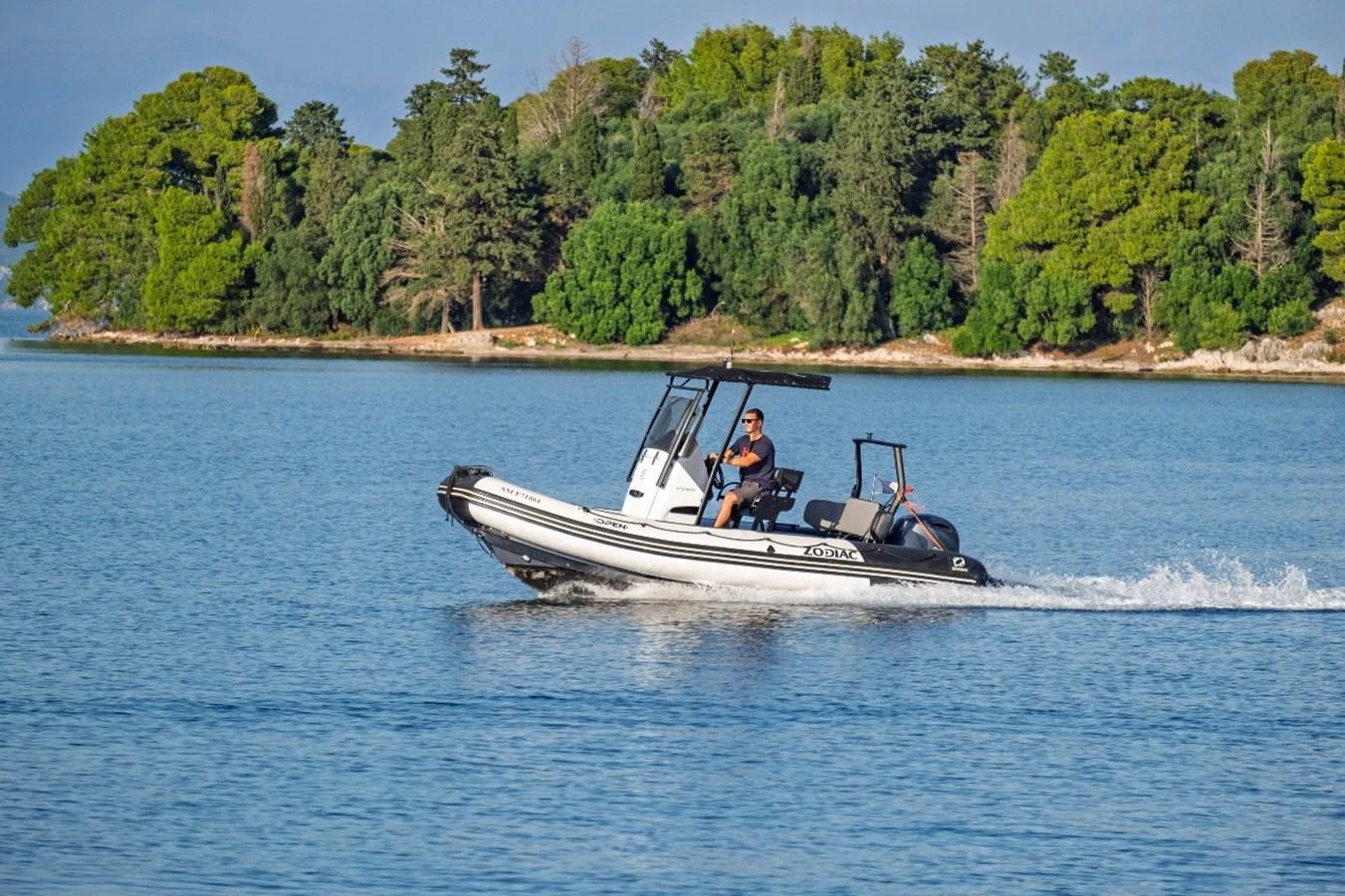 A sleek tender navigates calm waters with lush greenery in the background. aboard STALCA Yacht for Sale