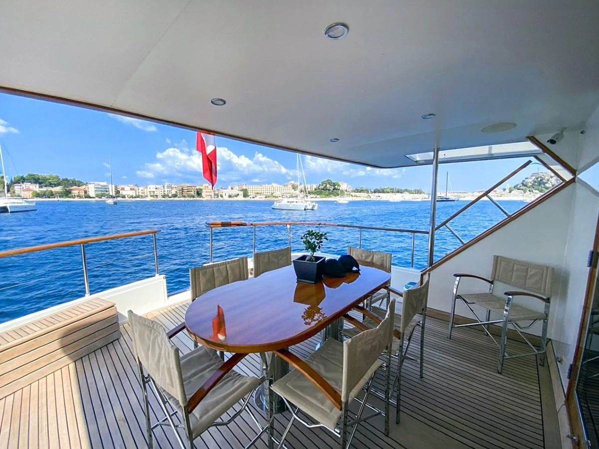 The aft deck features a stylish dining area with a polished wooden table and comfortable seating, offering stunning views of the surrounding waters. aboard STALCA Yacht for Sale