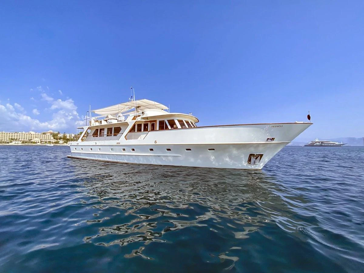 A classic yacht glides gracefully on calm waters under a clear blue sky. aboard STALCA Yacht for Sale