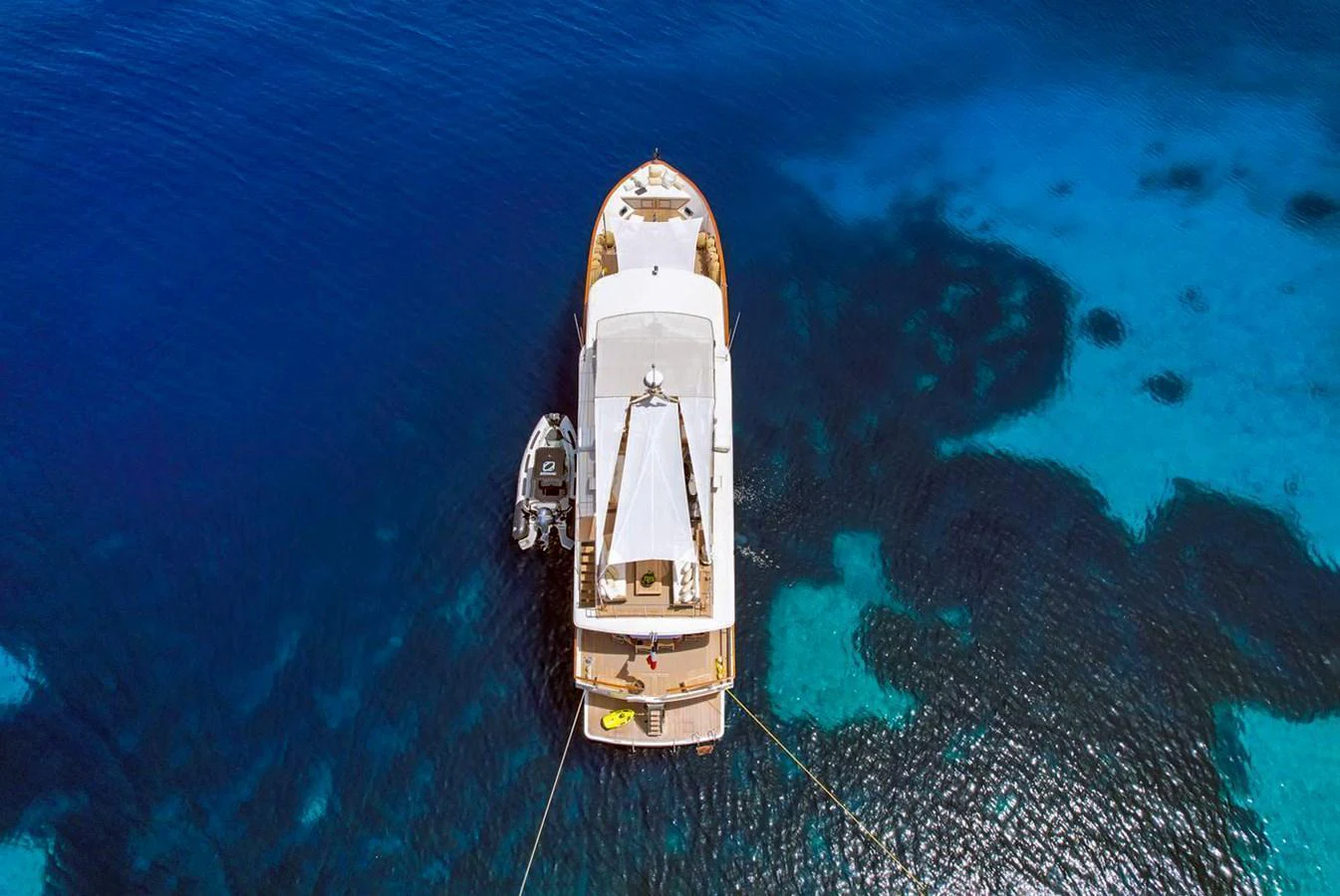 An aerial view of a yacht anchored in clear blue waters, showcasing its elegant design and surrounding marine beauty. aboard STALCA Yacht for Sale